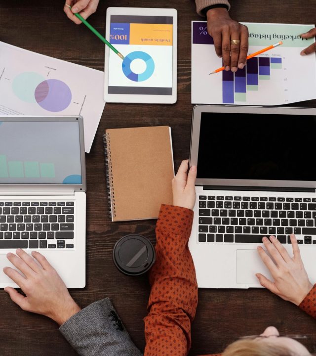 Overhead view of a team discussing digital marketing strategies with laptops and charts.